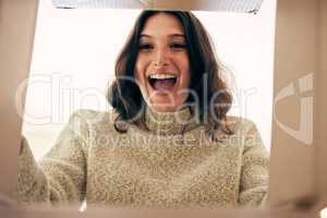 I didnt expect these to arrive so early. Shot of a young woman opening a cardboard box at home.