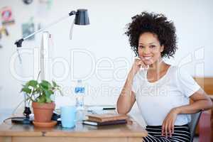 Portrait of an attractive young woman sitting at her workstation in the office. The commercial designs displayed in this image represent a simulation of a real product and have been changed or altered enough by our team of retouching and design specialist