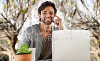 Cheery online morning. A handsome young man working on his laptop outdoors.