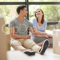 Taking our relationship to a whole new level. Shot of a happy young couple relaxing in their new home while moving in.