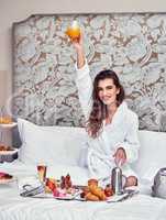 Heres to a good morning. Shot of an attractive young woman enjoying a luxurious breakfast in her room.