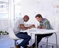 Accuracy is key. Shot of two male architects working together on building plans in the office.