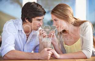 Sharing a milkshake. A young couple sharing a chocolate milkshake while on a date.