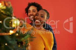 The perfect Christmas couple. Shot of a loving young couple decorating their Christmas tree.