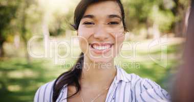 Her smile brightens up any day. Portrait of an attractive young woman taking a selfie while relaxing outdoors.