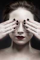 See no evil. A beautiful pale woman with dark lipstick covering her eyes.
