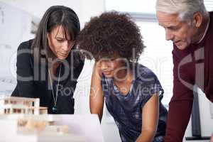 Touching up our prototype. Shot of three architects discussing an architectural model in the workplace.