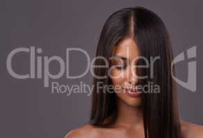 Its her crowning glory. A young woman with sleek hair posing in studio.