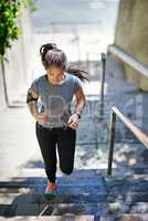 Shes stepping up her fitness routine. Shot of a fit young woman running up a flight of stairs.