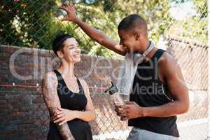Their chats are always cheerful. Shot of two sporty young people chatting to each other against a fence outdoors.