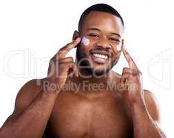 Treating my skin. Studio portrait of a handsome young man moisturizing his face against a white background.