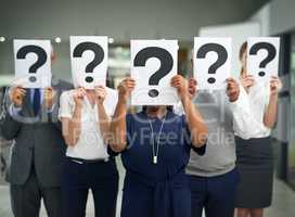 Business often produces more questions than answers. Shot of a group of businesspeople holding questions marks in front of their faces.