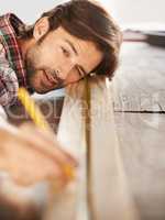 Everything has to be perfect. A handsome young carpenter measuring and marking wood.