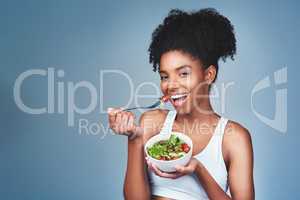 I like to enjoy my food guilt-free. Studio shot of an attractive young woman eating salad against a grey background.