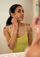 Removing dirt and oily buildup on her face. Cropped shot of a young woman cleaning her face with cotton wool in the bathroom.