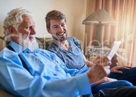 Next, well set up your email address. Shot of a young man showing his elderly grandfather how to use a tablet while sitting on the couch at home.