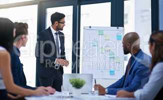 Time for him to pitch his idea to the team. Shot of a young businessman giving a demonstration on a white board to his colleagues in a modern office.