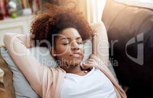 In a mellow state of mind. Shot of a young woman relaxing on the sofa at home.