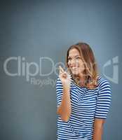Heres hoping.... Studio shot of a young woman crossing her fingers against a gray background.
