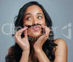 Let your hair do the talking. Studio shot of an attractive young woman making a moustache with her hair against a grey background.
