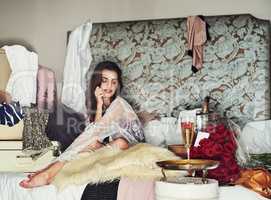 Girls have to treat themselves now and then. Shot of a beautiful young woman relaxing on her bed while being surrounded by gifts that she bought herself.