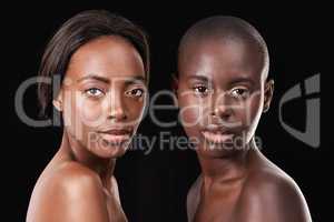 Intense beauty. Portrait of two beautiful african women standing together against a black background.