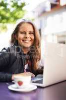 Enjoying the free wifi at the bistro. Portrait of a beautiful teen working on her laptop at a bistro.