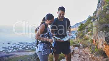 This is so helpful to plot out our hike path. Shot of a young couple using a guide book to complete a hike in a mountain range.