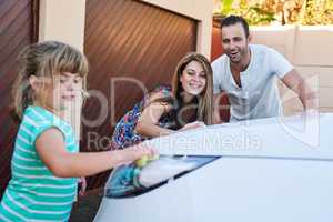 This car is going to be squeaky clean. Shot of a family washing their car in the driveway.