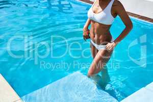 A dip in the pool will make all your worries go away. Cropped shot of an unrecognizable woman standing in a swimming pool.