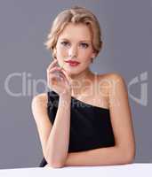 Shes flawlessly elegant. A gorgeous young woman in an evening gown while isolated on a grey background.