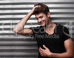 Handsome,stylish and relaxed. Shot of a handsome young man laughing while running his hand through his hair in front of metal shutters.
