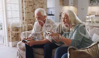 How did you do that. Shot of a senior couple sitting on the sofa at home together and gaming.