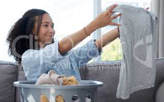 That detergent really did get all the stains out. Shot of a young woman folding away her freshly cleaned laundry at home.