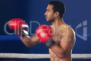 Hes got speed and power. Cropped shot of a handsome young male boxer striking swiftly during a fight in the ring.