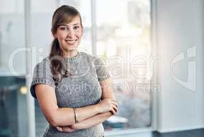 Young and driven to succeed. Portrait of a confident young businesswoman standing with her arms folded inside the office at work.