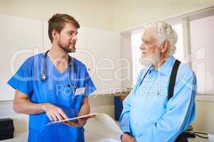 Well get to the bottom of your pain. Shot of a young doctor and his senior patient discussing his medical records together.