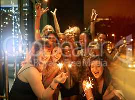 Sparkling into the New Year. Shot of a group of girlfriends having fun with sparklers on a balcony on a night out.