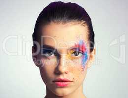 Full spectrum makeup. Studio shot of an attractive young woman posing with her face brightly painted.
