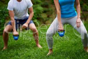 Working those muscles. Cropped shot of a man and woman using kettle bell weights in an outdoor exercise class.