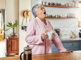 Oh heavens where is this pain coming from. Shot of a frightful looking elderly woman yelling out in pain and discomfort while drinking coffee in the kitchen.