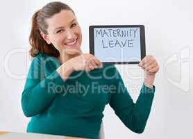 Shes expecting her baby soon. Shot of a pregnant woman holding up a tablet with the words maternity leave on the screen.