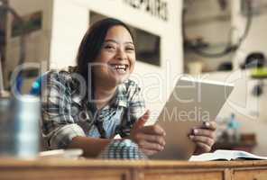 An infectious smile is already half the charm. Portrait of a young woman using a digital tablet at work.