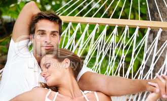 Content in one anothers company - VacationsGetaways. A appreciative and loving young couple relaxing on a hammock together - Copyspace.