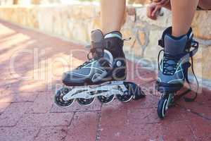 Time for these wheels to roll. Closeup shot of a young womans feet in rollerblades sitting on a park bench.