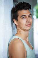 Youthful good looks. A handsome young man smiling at you while leaning against a wall.