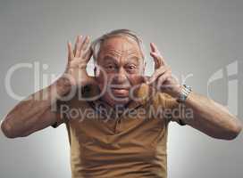 Int ouch with my inner child. Studio shot of an elderly man making a funny face against a grey background.