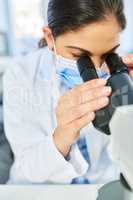 Science is a way to investigate and improve the world. Shot of a young scientist using a microscope in a lab.