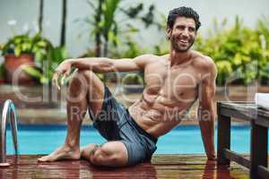 That was a great swim, now time to chill. Shot of a handsome young shirtless man chilling by the poolside at home.