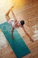 Perfection the balance between mind and body. High angle shot of a young woman doing yoga indoors.